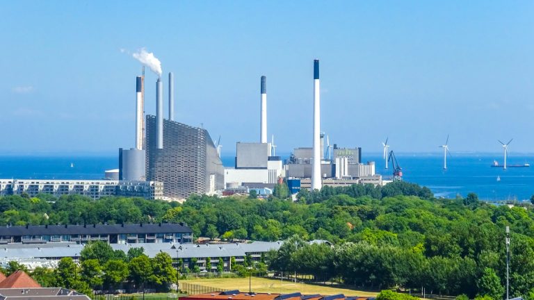 Usina industrial com chaminés e turbinas eólicas ilustrando o GHG Protocol